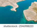 Aerial view of coastline of Pag and Veli Sikavac islands, Croatia. The contrast of clear turquoise water of Adriatic Sea and the winding rocky coastline of the islands. Concept travel in Croatia