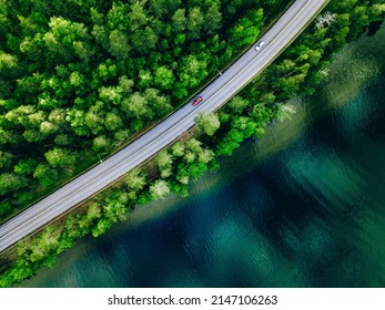 Aerial view of coastline road with green woods and blue lakes water in summer Finland.