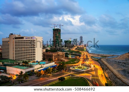 Aerial view of Colombo, Sri Lanka modern buildings with coastal promenade area. Car traffic during the night. Sunset sky and ocean waves