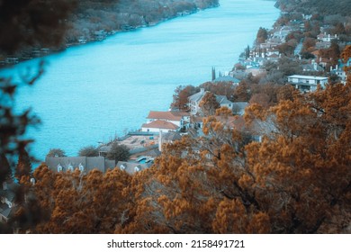 An Aerial View Of The Colorado River With Buildings And Dense Vegetation On Both Sides In Austin, Texas