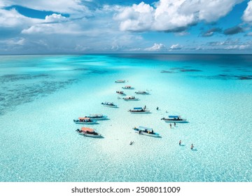 Aerial view of colorful boats in clear azure water in summer. Mnemba island, Zanzibar. Top view of sandbank in low tide, blue sea, white sand, swimming people, yachts, dramatic sky with clouds. Ocean - Powered by Shutterstock