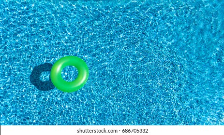 Aerial view of colorful inflatable ring donut toy in swimming pool water from above, family vacation concept background
