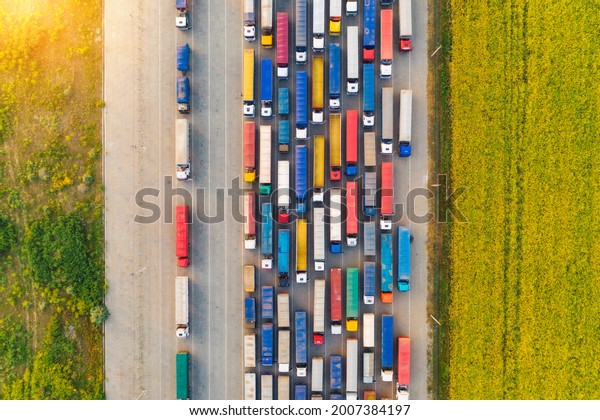 Aerial view of colorful trucks in terminal at\
sunset in summer. Top view of logistic center. Heavy industry.\
Transportation. Cargo transport, shipping. International trucking.\
View from drone of truck