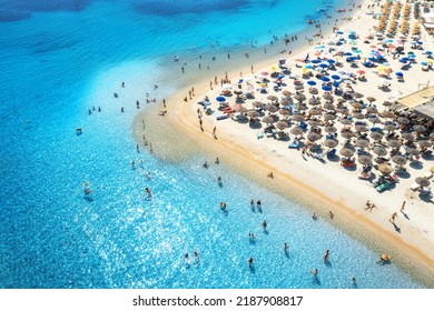 Aerial View Of Colorful Umbrellas On Sandy Beach, People In Blue Sea At Sunset In Summer. Tuerredda Beach, Sardinia, Italy. Tropical Landscape With Turquoise Water. Travel And Vacation. Top View	