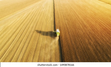 Aerial view of combine harvester harvesting wheat. Beautiful wheat field at sunset. Combine harvester working on the large wheat field.