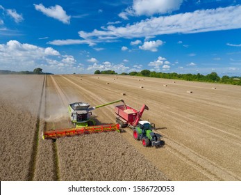 Aerial View Of Combine Harvester Harvesting Wheat And Filling Tractor Trailer With Grain