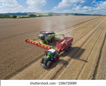 Aerial View Of Combine Harvester Harvesting Wheat And Filling Tractor Trailer With Grain