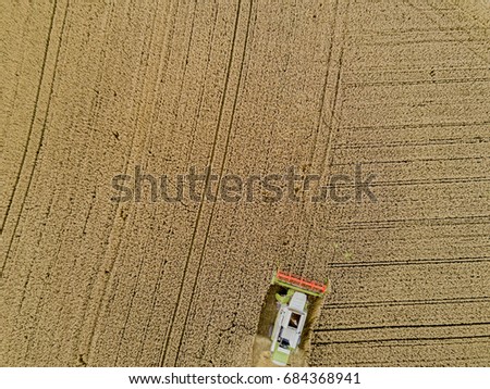 Similar – A combine harvester is harvesting grain crops on a cornfield in the evening sun seen from above