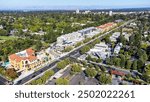 Aerial view of commercial and residential areas of Menlo Park, California toward Palo Alto along El Camino Real Rod near Middle Avenue. Backdrop distant San Francisco Bay and mountains