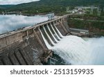 Aerial view of concrete dam releasing water into river on cloudy day. Water discharge at hydroelectric power plant.