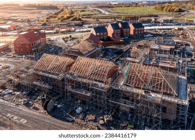 Aerial view of a construction site with new build, energy efficient homes being built with the roof rafters exposed and surrounded by scaffold with copy space