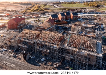 Aerial view of a construction site with new build, energy efficient homes being built with the roof rafters exposed and surrounded by scaffold with copy space