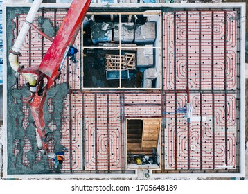 Aerial View Of Construction Workers Pouring A Wet Concrete At Floor Heating System Installation In New House Construction Site