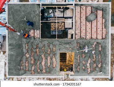 Aerial View Of Construction Workers Pouring A Wet Concrete At Floor Heating System Installation In New House Construction Site