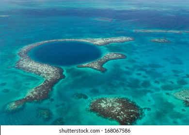 An Aerial View Of The Coral Reef And Deep Cave That Make Up The Famous Diving Spot Of The Blue Hole In The Caribbean Ocean Off The Coast Of Belize.