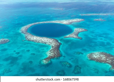 An Aerial View Of The Coral Reef And Deep Cave That Make Up The Famous Diving Spot Of The Blue Hole In The Caribbean Ocean Off The Coast Of Belize.