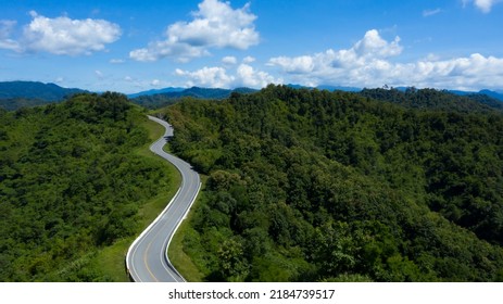 Aerial view of country asphalt road in forest. Drone flying over curved country road in the mountain.