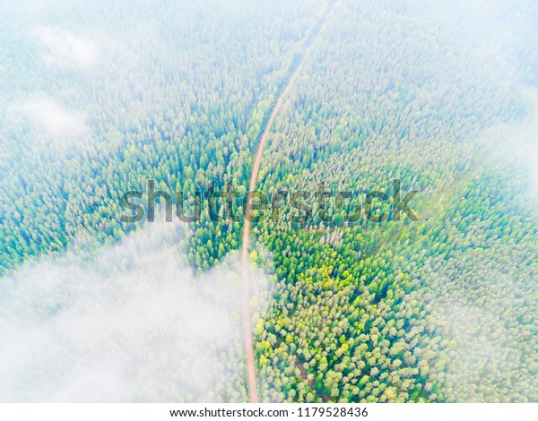 Aerial\
view of a country road in the forest. Beautiful landscape. Clouds\
over the green forest and road. Aerial bird\'s eye road. Aerial top\
view forest. Texture of forest view from\
above.