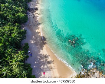 Aerial view of cozy white sand beach with turquoise clear sea water, and some people on the beach. Banana Beach, Phuket, Thailand.