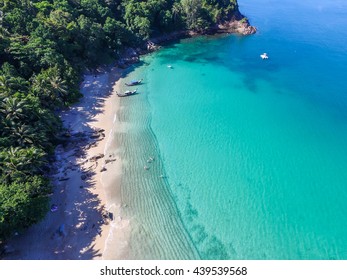Aerial view of cozy white sand beach with turquoise clear sea water, and two traditional longtail boat. Banana Beach, Phuket, Thailand.