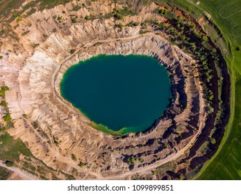 Aerial view of a crater created by mining machines and filled up with water creating an artificial lake.