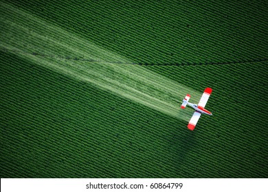 An aerial view of a crop duster or aerial applicator, flying low, and spraying agricultural chemicals, over lush green potato fields in Idaho. - Shutterstock ID 60864799