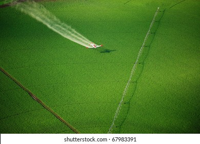 Aerial View Of A Crop Duster Spraying A Farm Field