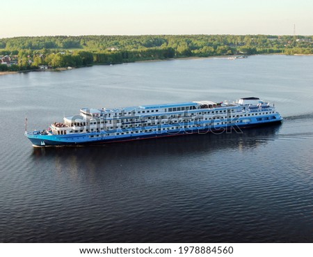 Aerial view cruise ship sails along the river surrounded by a beautiful green forest in the summer at sunset. Cruise Ship Vacation. 