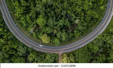 Aerial view of curve green forest road at South East Asia, Aerial view of a provincial asphalt street road adventure passing through a forest with car, Thailand.