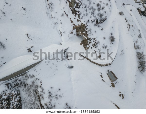 Aerial view of curved and snow covered road\
in winter landscape in\
Switzerland