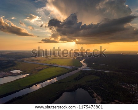 Aerial view of dark cloud with heavy raining over the green forest and river, sunset with rain storm. 