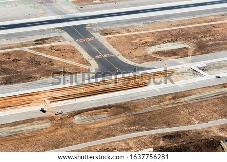 Aerial view of development construction in taxiway and runway in an international airport. Asphalt and concrete material for infrastructure and expansion work. 
