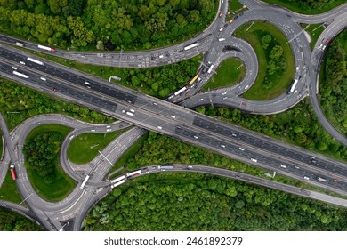 Aerial view directly above a busy M62 UK motorway intersection with roundabout and overbridge cutting through green woodland in an environmental disaster image - Powered by Shutterstock