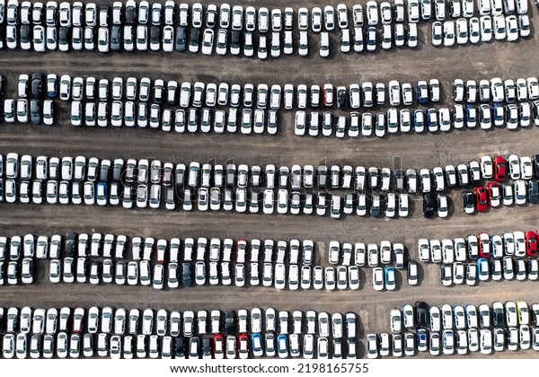An aerial view directly above rows of newly built\
cars and vehicles ready for export and import and delivery to sales\
dealerships on docks 
