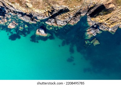 Aerial View Directly Above Rugged Rocky Outcrop Of Land Jutting Into A, Emerald Green Ocean With Sand Sea Bed