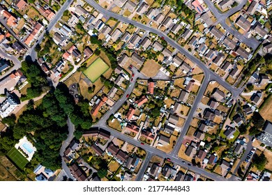 An aerial view directly above a suburban community on the outskirts of a city with intertwining roads and neighbourhoods