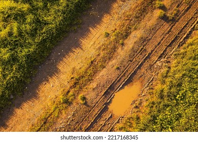 Aerial view of dirt road with a puddle. Top down view of countryside path. Background texture concept. - Powered by Shutterstock