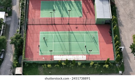 Aerial view of diverse male tennis players playing match on sunny outdoor court, copy space - Powered by Shutterstock