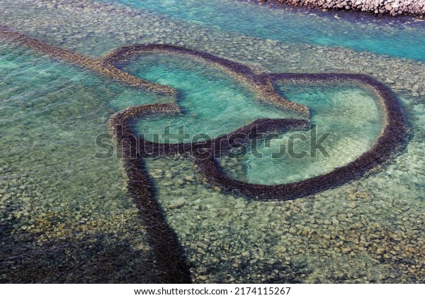 Aerial view of the Double-Heart Stacked Stones or\
the Twin-Heart Fish Trap bathed in the turquoise sea water, which\
is a fishing weir and now a popular tourist attraction, in Cimei,\
Penghu, Taiwan