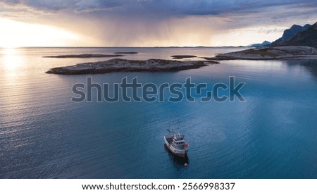 Aerial view of Dramatic evening storm clouds at stunning evening in Northern Norway pouring rain with fisher boat in the bay