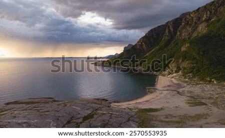 Aerial view of Dramatic evening storm clouds at stunning evening over the beach at Mjelle in Northern Norway pouring rain with fisher boat in the bay