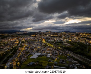 Aerial view of dramatic storm clouds over sprawling town lights at dawn