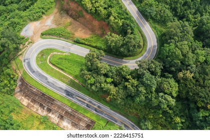 Aerial view drone fly over countryside road passing through the green forest and mountain in Thailand. Mountain winding zig zag road. Top aerial view