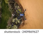 Aerial view of a drone flying over green summer farm fields, crops or pasture with road.