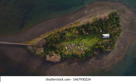 Aerial View With Drone Of The Iconic Aucar Island That Has A Bridge Made Of Wood. This Island That Is Near The Town Of Quemchi In The Chiloé Archipelago 