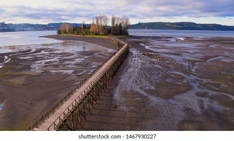 Aerial View With Drone Of The Iconic Aucar Island That Has A Bridge Made Of Wood. This Island That Is Near The Town Of Quemchi In The Chiloé Archipelago 