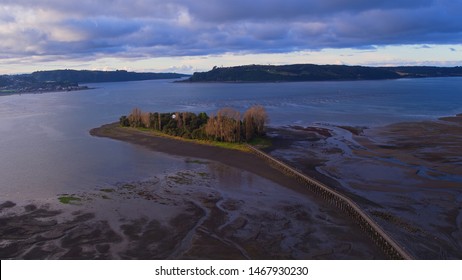 Aerial View With Drone Of The Iconic Aucar Island That Has A Bridge Made Of Wood. This Island That Is Near The Town Of Quemchi In The Chiloé Archipelago 