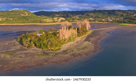 Aerial View With Drone Of The Iconic Aucar Island That Has A Bridge Made Of Wood. This Island That Is Near The Town Of Quemchi In The Chiloé Archipelago 