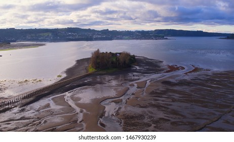 Aerial View With Drone Of The Iconic Aucar Island That Has A Bridge Made Of Wood. This Island That Is Near The Town Of Quemchi In The Chiloé Archipelago 