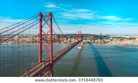 Aerial view or drone photo of the 25 De Abril Bridge. Red Lisbon bridge is connecting Lisbon city and Almada across the Tajo river. Portugal sightseeing.